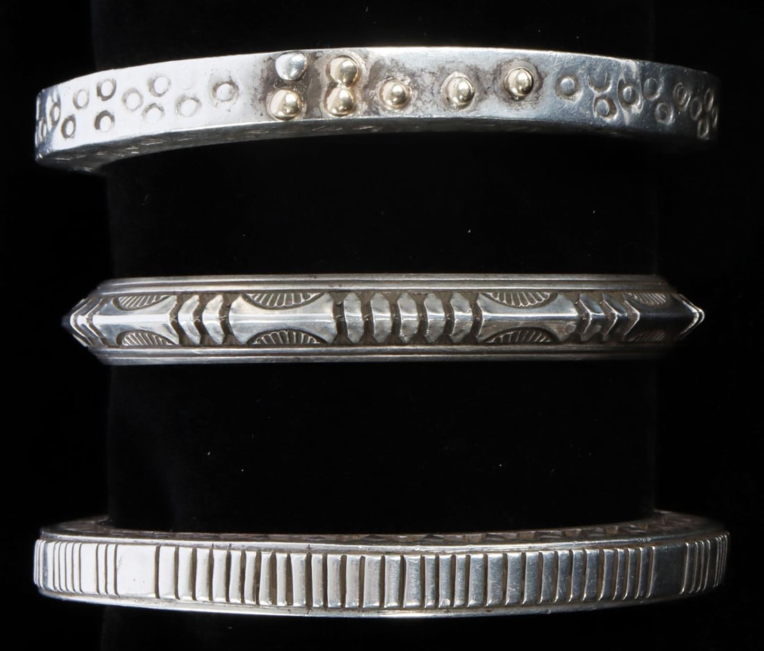 LOT OF 3 HEAVY SILVER NAVAJO & MEXICAN BANGLES: Lot of THREE (3) silver bangles for women. 1) Silver bangle with one silver seven, 14K gold droplets on front. Geometric stamps on either side of the bangle, circular stamping on top. Bangle is marked