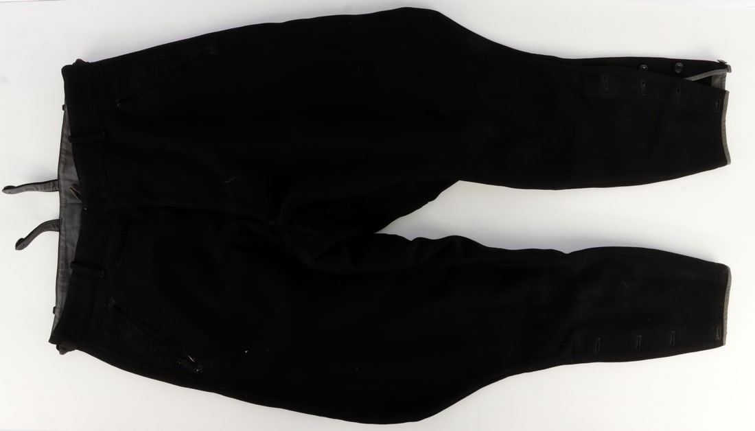 WWII GERMAN THIRD REICH BLACK UNIFORM BREECHES: Uniform breeches for either the Waffen-SS or a panzer division of the Wehrmacht. Shows evidence of tearing, wearing, and repair. With belt loops and garter mounts. Gray band woven to end of leg. 32 in