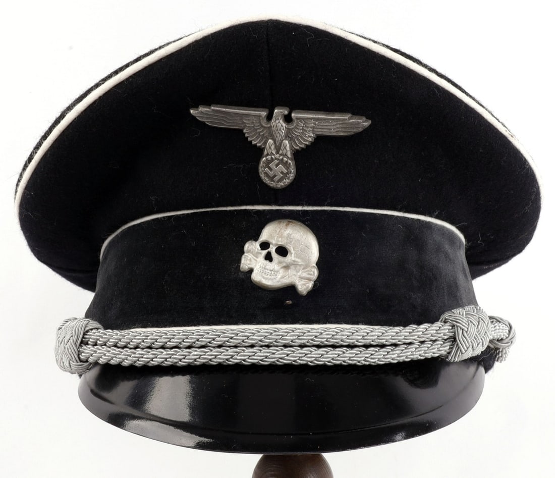 WWII GERMAN EARLY SS OFFICERS VISOR CAP: Black wool exterior with white piping and black doeskin band. Bullion cord and and pressed fiber visor. Artificial silk liner with celluloid diamond and SS runes in metallic gold. Totenkopf insignia m
