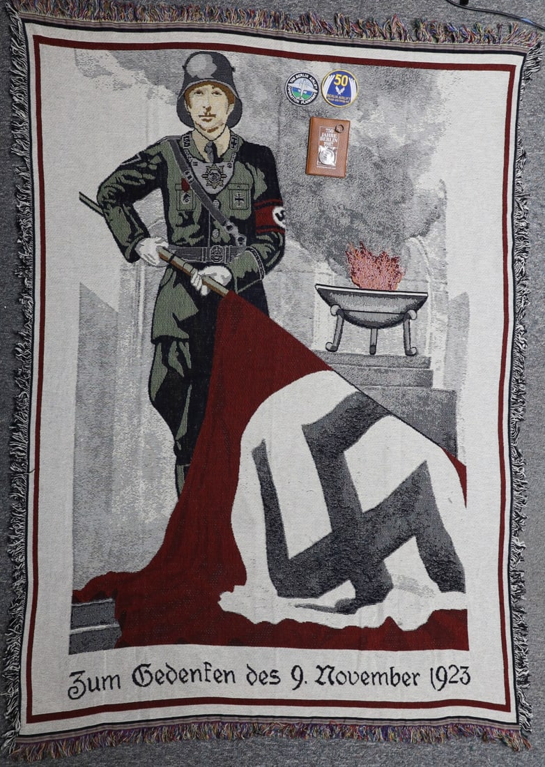 WW2 GERMANJAKOB GRIMMINGER BLOOD FLAG TAPESTRY: Finely woven post-war tapestry depicting SS-Standartenfuhrer Jakob Grimminger holding the blutfahne (blood flag) in front of a flaming brazier. The bottom of the tapestry bears the date of the Beer Ha