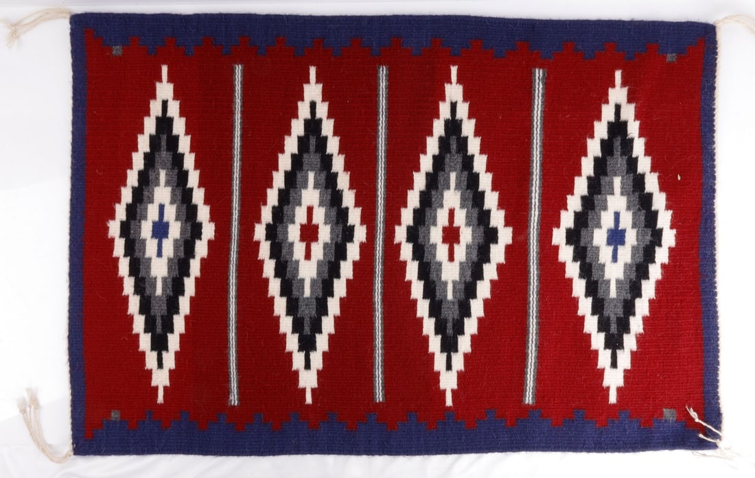 NATIVE AMERICAN NAVAJO DIAMOND DESIGN BY JAMES: A Navajo rug showing four diamonds. Red field, with white, black, gray, and red accents edged by white yarn. Woven by Navajo weaver Riva James. This was hung from a wall for display, and was not place