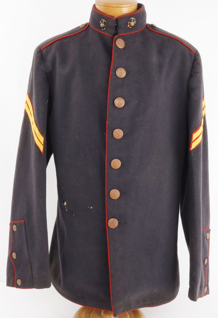 WWI US MARINE CORPS DRESS BLUES UNIFORM TUNIC: WWI USMC corporal's dress blues uniform tunic of dark blue wool with red piping and golden chevrons. Retains buttons and collar insignia. Front closure buttons marked "J.C.L Shabeck, Prov. R.I." Very