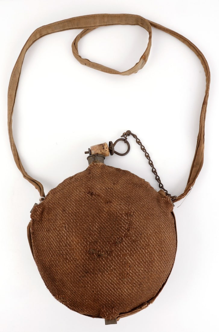 US CIVIL WAR CSA ST LOUIS SMOOTH SIDE CANTEEN: Model 1858 smooth side canteen with wool cloth cover, marked as a product of the St. Louis Arsenal. Brown fabric strap remains intact. Cork plug is intact. There is some mothing to the fabric, and som