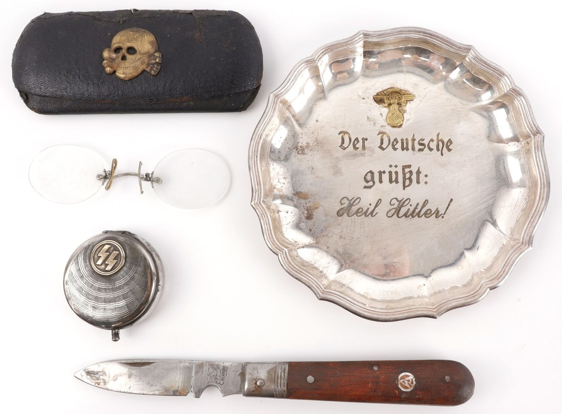 WWII GERMAN THIRD REICH PERSONAL EFFECTS LOT OF 4: 1) SA pocket knife. 2) Waffen-SS glass case with glasses, adorned with a Totenkopf. 3) SS pocket ashtray. 4) Display plate reading "Der Deutsche grust: Heil Hitler" (The German Greeting: Heil Hitler).
