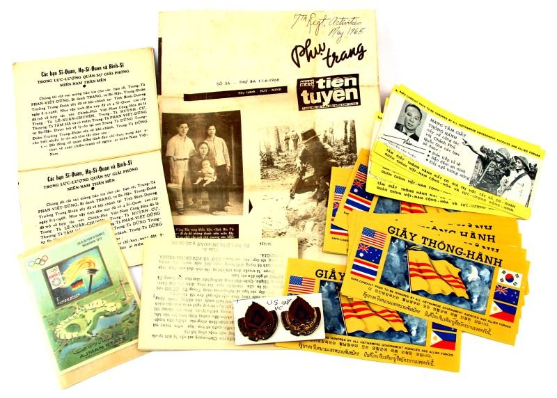 GROUPING OF VIETNAM WAR SOUVENIRS & EPHEMERA: Lot consisting of 189th Support Battalion Distinctive Unit Insignia, 28 Chieu Hoi program safe conduct passes, leaflets written in Vietnamese, and Vietnamese newsletter.