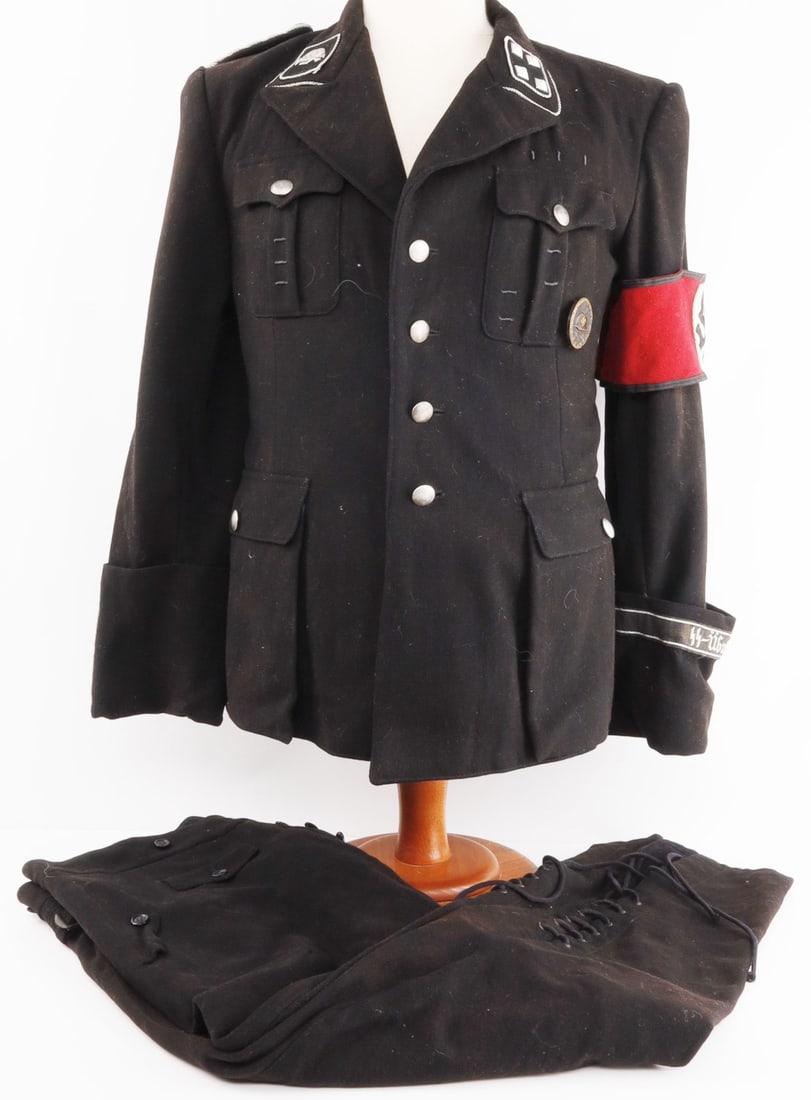 WWII GERMAN NAMED SS OFFICER DACHAU TUNIC: Sturmbannfuhrer ranked tunic. Includes collar tabs, shoulder board, a Wound badge, SS armband with RZM tag, pebbled buttons marked Assmann and 79mm, SS Ubunslager Dachau cuff title. Right interior poc