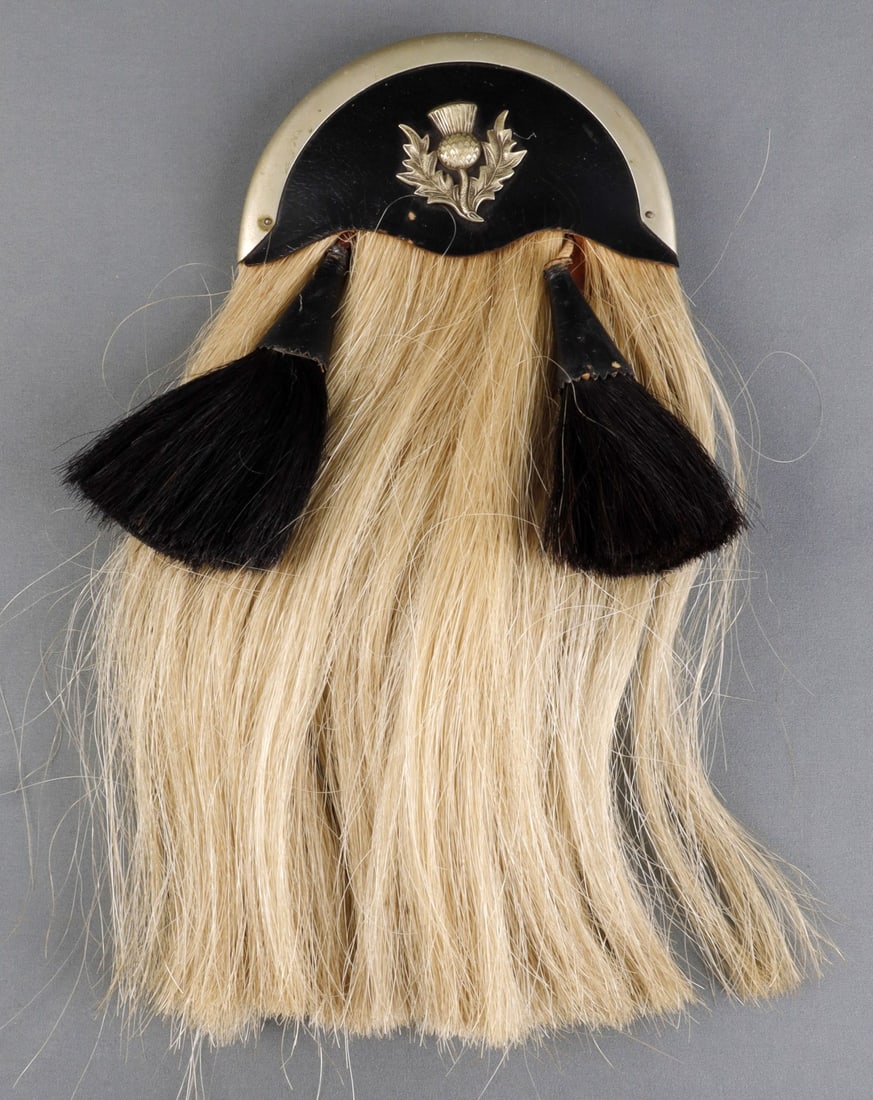 R.G. LAWRIE HORSEHAIR DRESS SPORRAN THISTLE BADGE: Scottish horsehair & leather sporran with silver plate thistle badge. Reverse has maker's mark "R.G. Lawrie, Made in Scotland." White horsehair body with two black tassels. Belt loop on reverse. 14 in