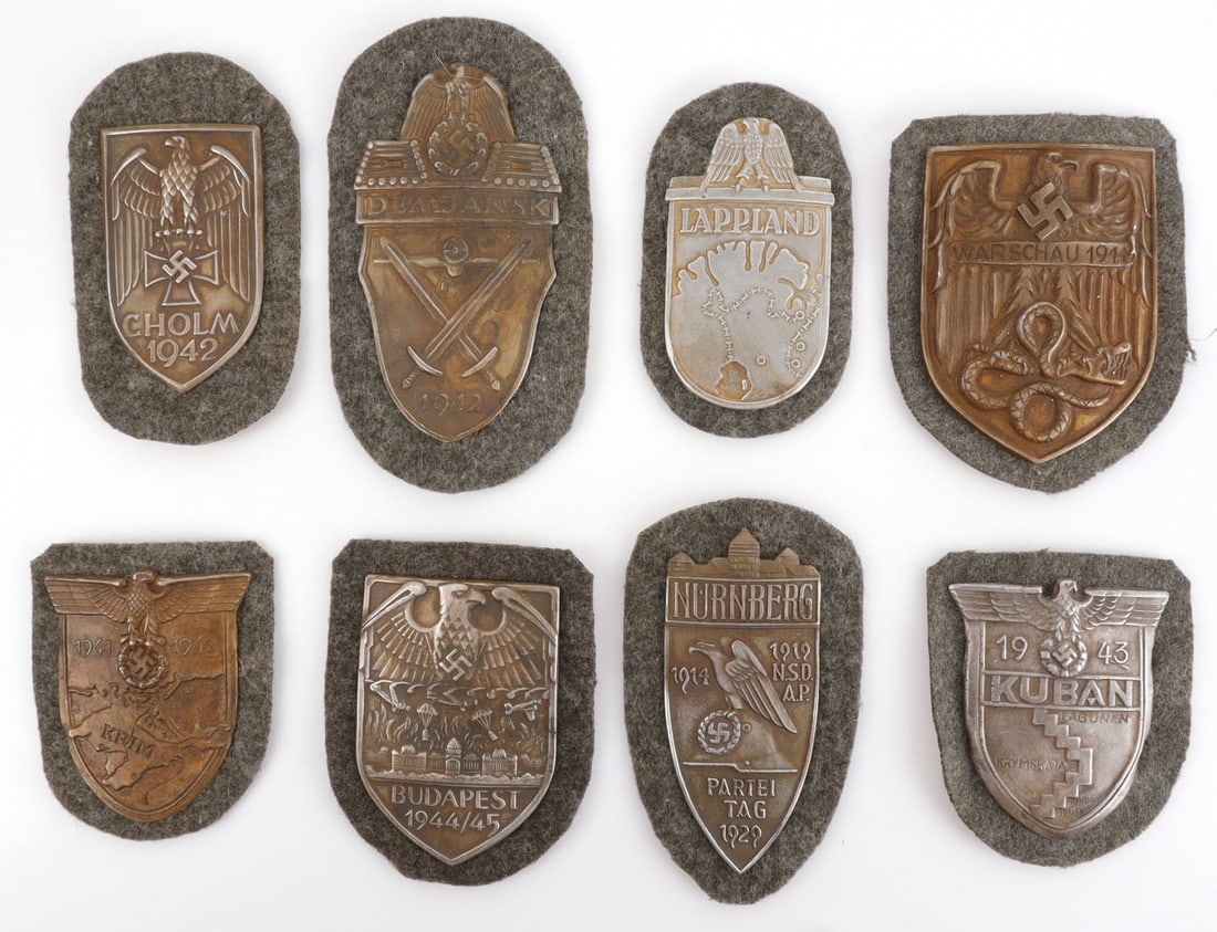 LOT OF 8 WWII GERMAN THIRD REICH CAMPAIGN SHIELDS: Lot of EIGHT (8). Campaign shields for Nurnberg, Cholm, Kuban, Warsaw, Krim, Budapest, Lappland, and Demjansk. Unauthenticated, sold "as is."
