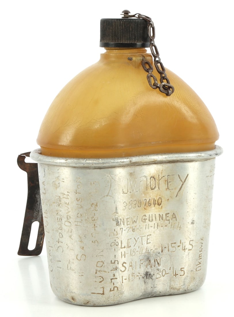 WWII NAMED & BATTLE ETCHED U.S. 1944 DATED CANTEEN: Celluloid canteen, cup is stamped U.S. 1944. Named to J.V. Flory S/N 38307640. He etched all his duty stations, from Taccoa, Ga. to Tokyo, Japan. This lot has a reserve.