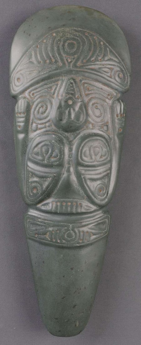 PRECOLUMBIAN TAINO CARVED CELT AXE HEAD: Pre-Columbian Taino (1000-1500 CE) carved ceremonial axe head, commonly known as a celt. This celt is carved with an incredibly abstract figure, possibly depicting either a standing, smiling figure or