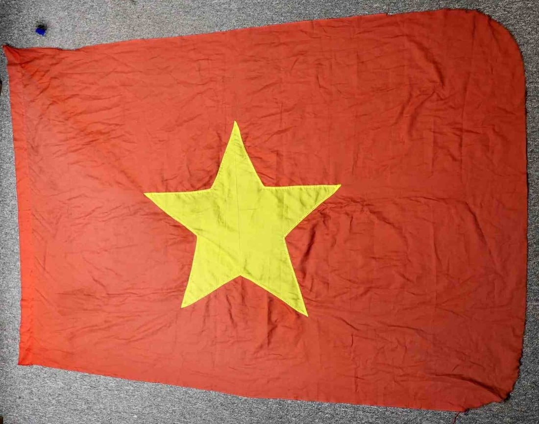 VIETNAM WAR NORTH VIETNAM NATIONAL FLAG: A flag for North Vietnam, age appropriate to the Vietnam War. A silken yellow star on a red field. Tearing and running along the edges. 79 x 57inches. Very good, original condition.