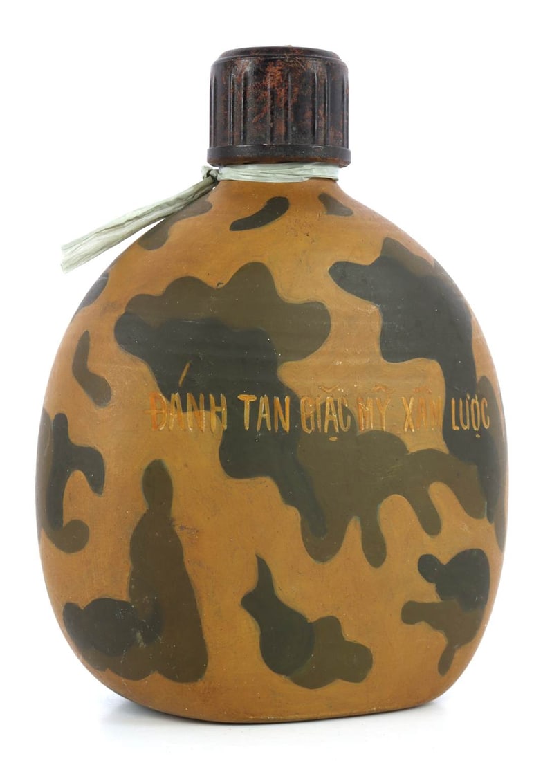 VIETNAM WAR VIET CONG PAINTED CANTEEN KHE SANH: A Viet Cong canteen painted to show Viet Cong slogans and Viet Cong fighters. Reads on one side "Danh Tan Giac My Xam Luoc.' The other side reads 'Khe Sanh 1968.' 5 X 7.25 inches. Very good, original
