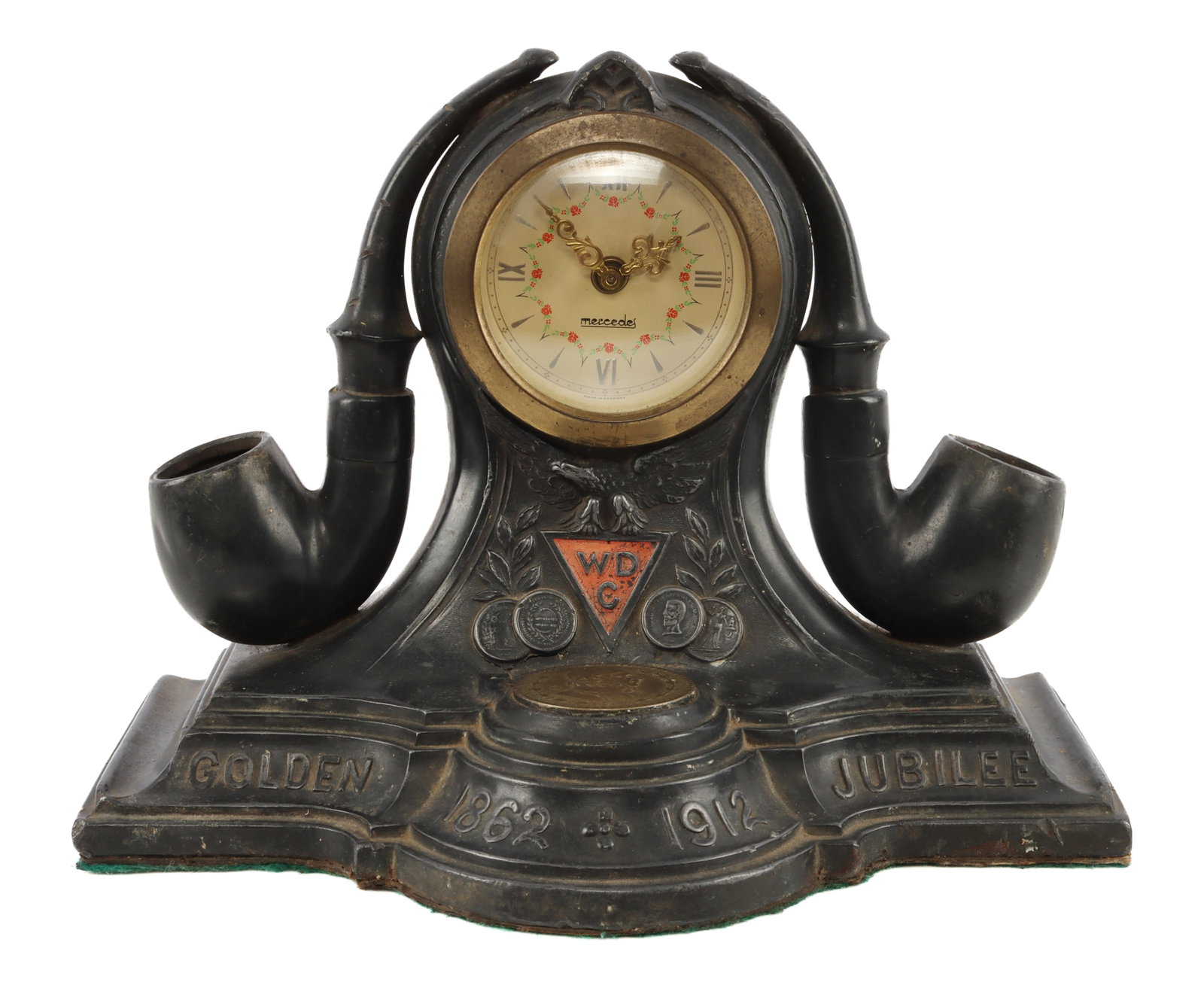DEMUTH TOBACCO COMPANY GOLDEN JUBILEE CLOCK: A William C. Demuth Tobacco Company table clock, celebrating its Golden Jubilee. Bears the inscription 'Golden 1862-1912 Jubilee' and prominently features two mounted pipes. Original ink well has been
