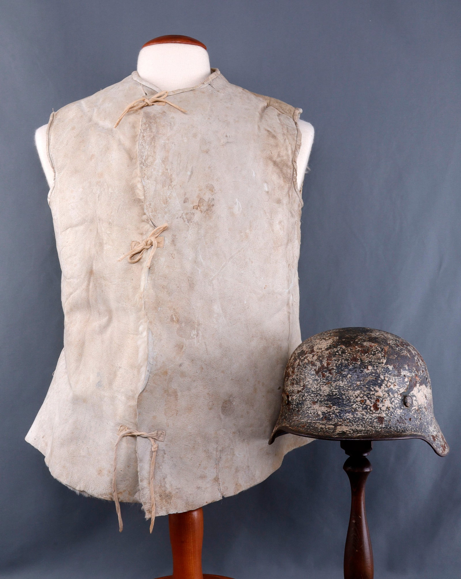 WWII GERMAN NAMED M40 SNOW CAMO HELMET & VEST: Original M40 German helmet from the eastern front. Condition makes it impossible to discern factory marks. Painted name "Gruttner' on interior. Comes with German sheep skin winter vest. This lot has a