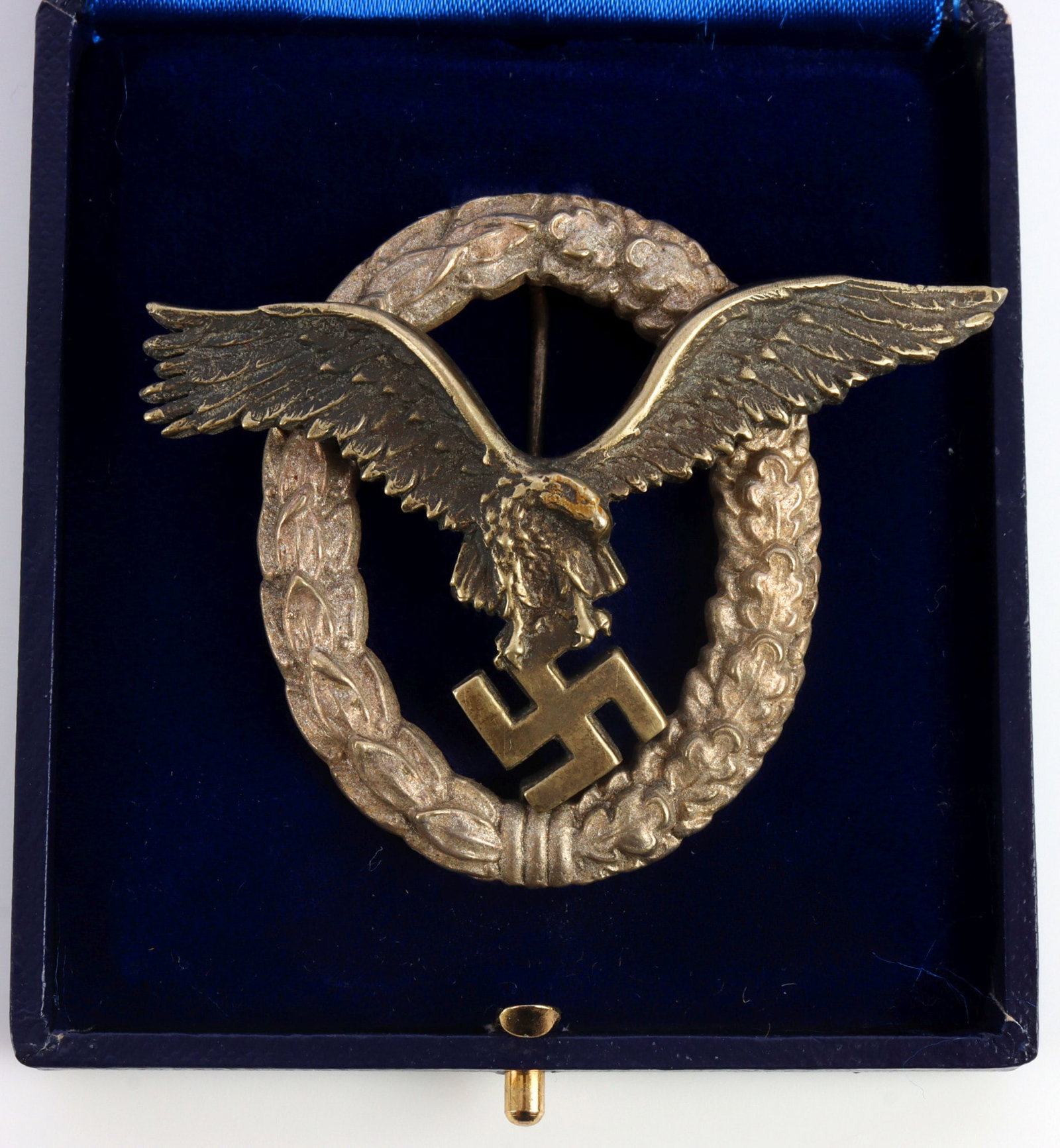WWII GERMAN CASED LUFTWAFFE PILOT'S BADGE JMME: Cased Luftwaffe pilot's badge. Two-piece construction, non-magnetic. Vertical thin wire pin. Reverse has maker's mark "JMME" and two domed rivets. Height 2 inches. Width 2.5 inches. Good condition, so
