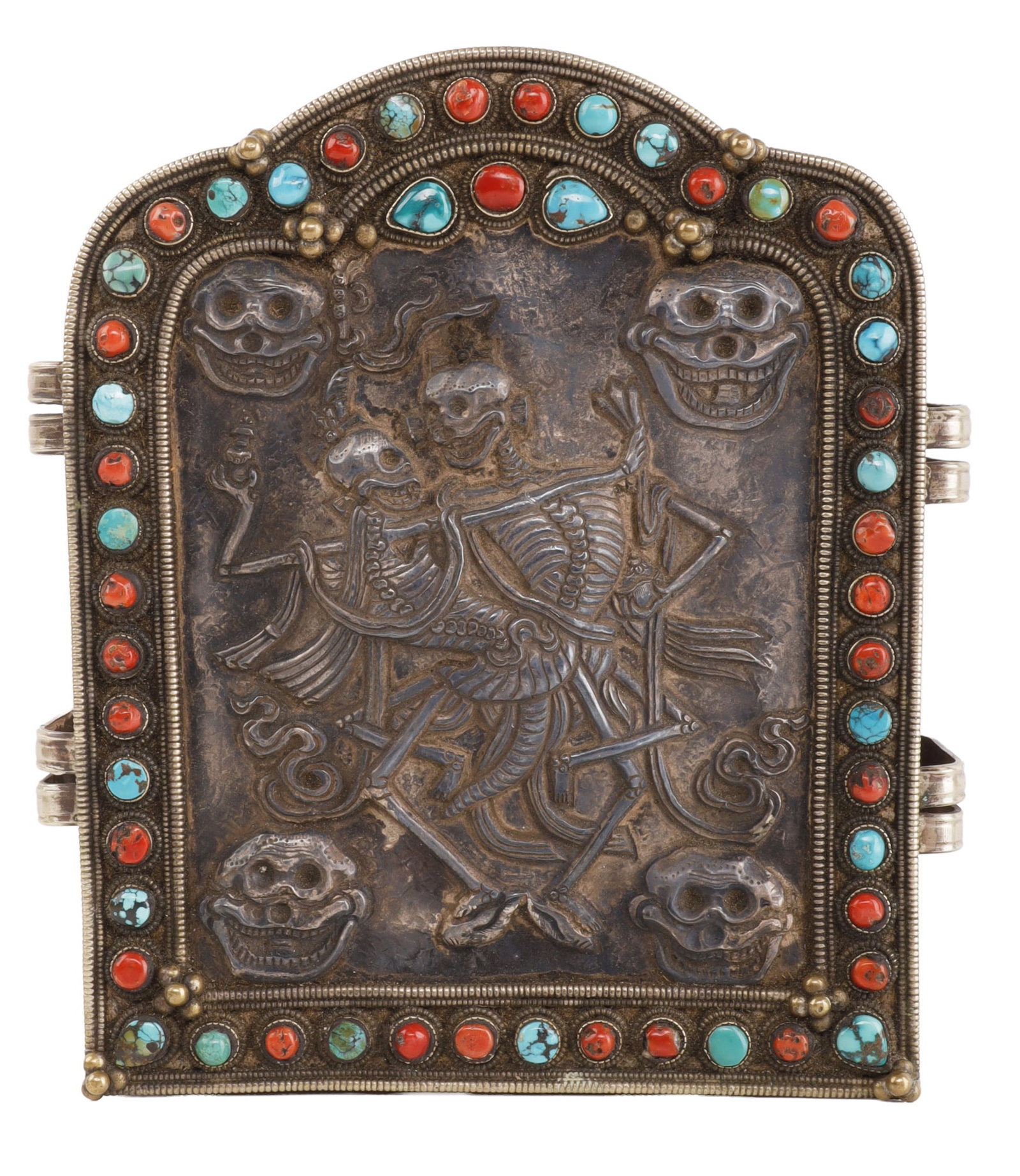 TIBETAN GAO PORTABLE SHRINE WITH DANCING SKELETONS: A Tibetan ghau or gao box, a type of portable shrine, depicting the chitipati, or 'dancing skeletons' motif. Cover is silver, body is brass, with inlaid turquoise and coral stones. Box is soldered shu
