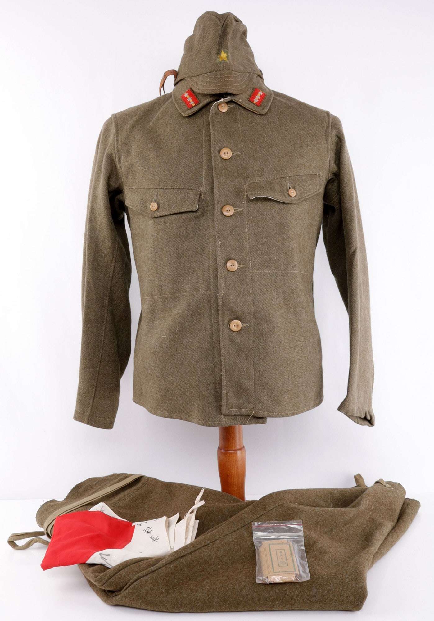 IMPERIAL JAPANESE ARMY COLONEL UNIFORM WITH FLAG: An Imperial Japanese Army colonel's uniform: pants, tunic, and cap. With the uniform comes two additional items: 1) A signed 'good luck' Imperial Japanese flag. 2) A half-smoked pack of Japanese cigar