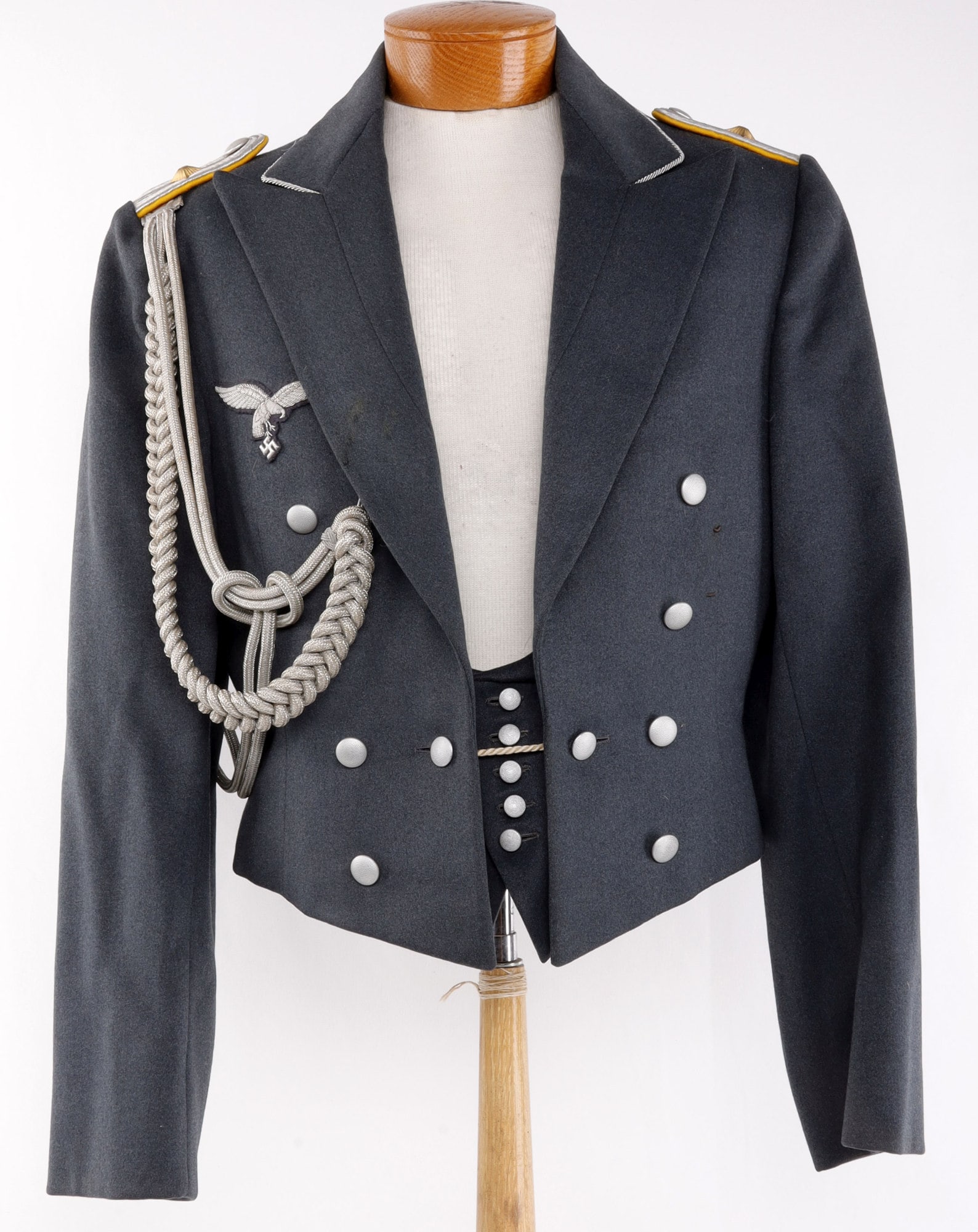 NAMED LUFTWAFFE OBERLEUTNANT EVENING TUNIC: Luftwaffe evening dress tunic and vest. Standard blue wool with shoulder boards, silver bullion piping, bullion patch, and bullion aguillette. Karl Schulz make. Tunic is small. Dated 1938 and features