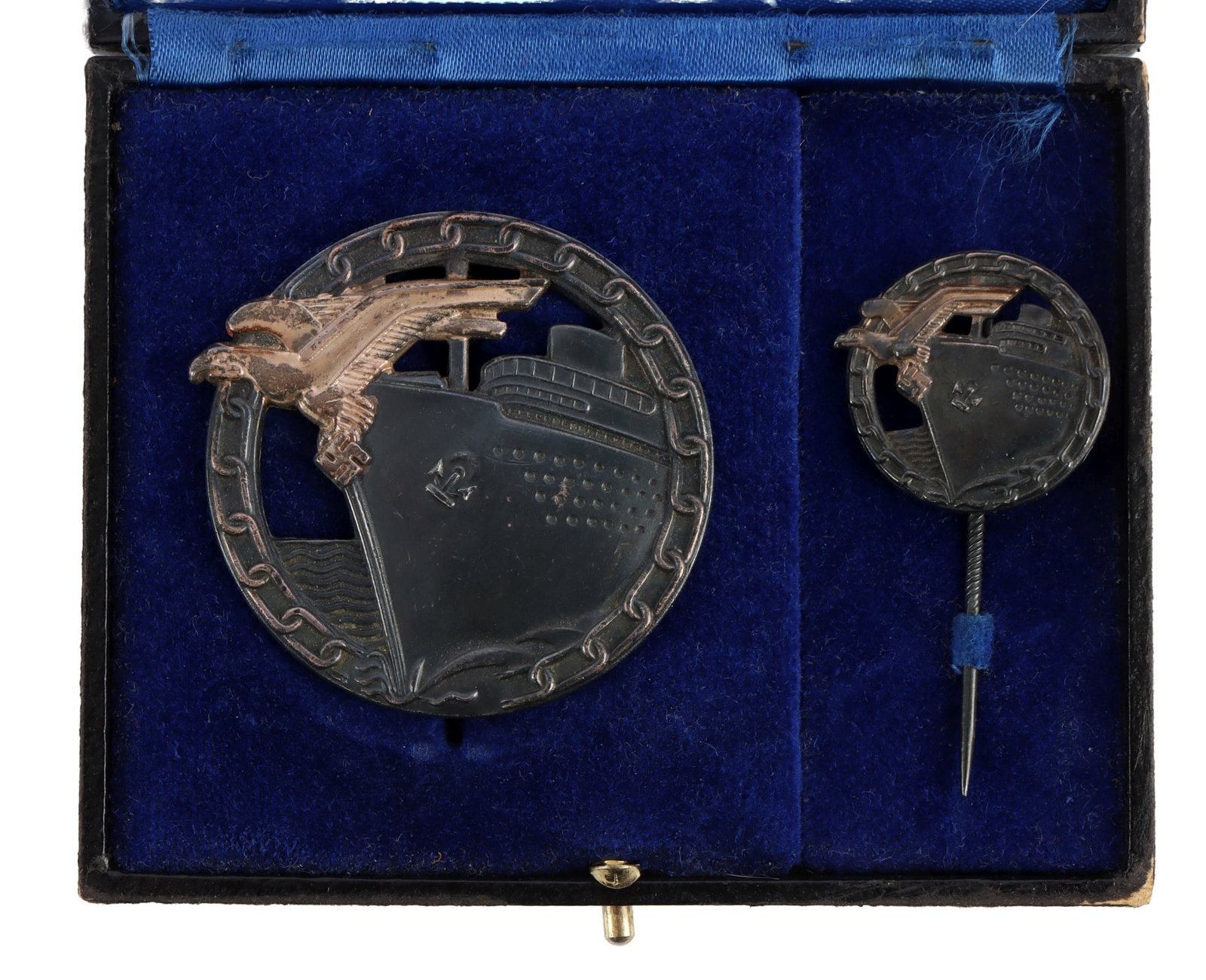 CASED KRIEGSMARINE BLOCKADE RUNNER BADGE SET: Cased set, Kriegsmarine Block Runner Badge with matching miniature on gnurled stick pin. Badge reverse marked "Fec. Otto Placzek Berlin Ausf. A.G.M.u.K.4 Gablonz." Blackened and silvered tombak constr
