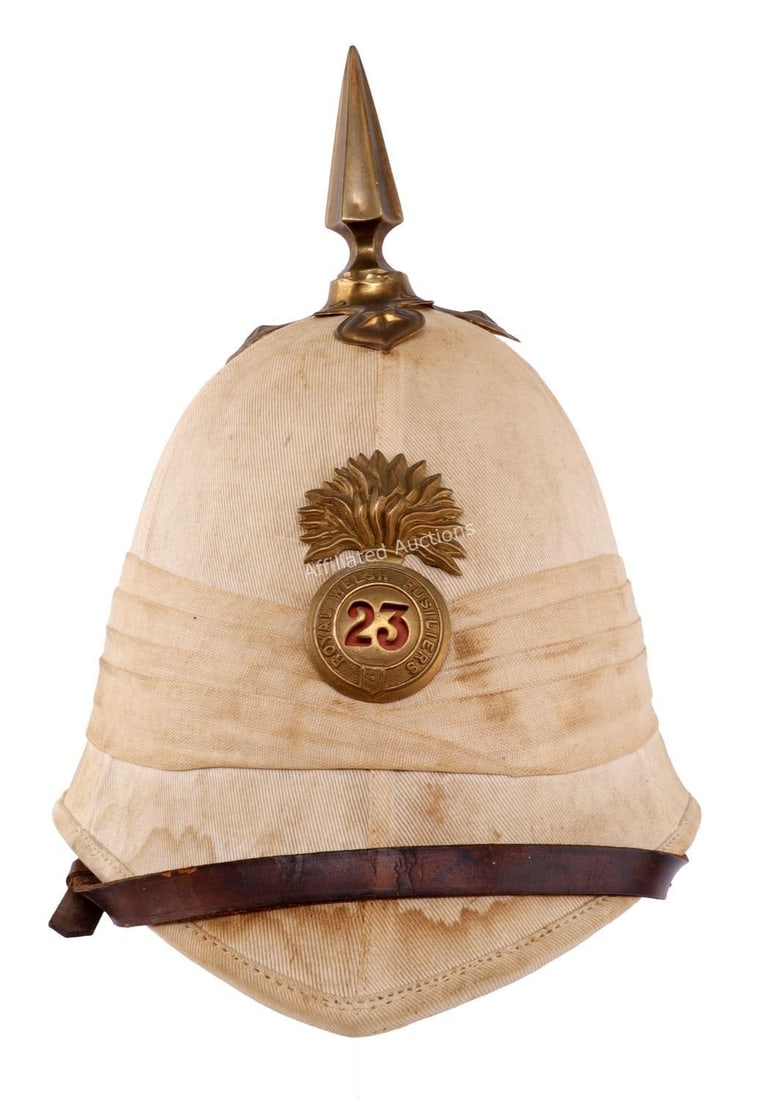 ROYAL WELSH FUSILIERS FOREIGN SERVICE HELMET: British pith sun helmet with badge of the 23rd Regiment of Foot, or Royal Welsh Fusiliers. Brass spike, leather chinstrap. Opening measures 7.5 inches front to back. Very good condition.