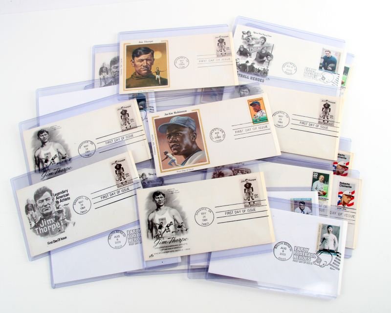 FIRST DAY ISSUE SPORTS MEMORABILIA STAMPS: Stamps include Roberto Clemente, Jackie Robinson, Jim Thorpe, Bronko Nagurski, Ernie Nevers, Knute Rockne, Walter Camp, and Red Grange. Twenty Three in total. Overall in very good condition.