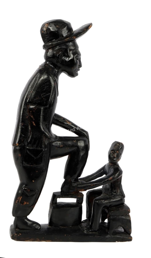 BLACK AMERICAN ART DEPICTING A SHOE SHINE: A wooden statue depicting a shoe shiner and customer. The figures are painted black. Some paint loss. Approximately 9 X 16 inches. Very good, original condition.