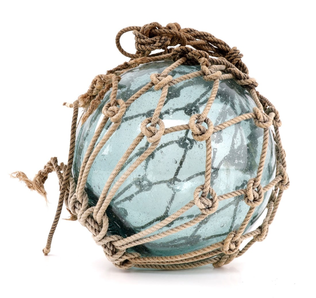 MID 20TH CENTURY JAPANESE FISHING FLOATS IN NET: A Japanese fishing float, wrapped in knotted netting, likely mid-20th century. This float was recovered from a beach on Iwo Jima from the 1960s, per previous owner. 9 inches tall, 10 inches diameter. 