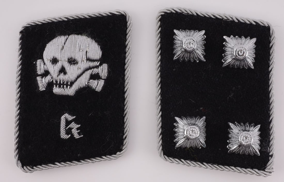 GERMAN SS-TV K COLLAR TAB CAMP ADMIN. OFFICER: Collar tab pair. First has Totenkopf over "K" embroidered in aluminum wire thread. Second has four pips, split pin retention. Both bordered with twisted aluminum wire piping. Black wool on woven blue-