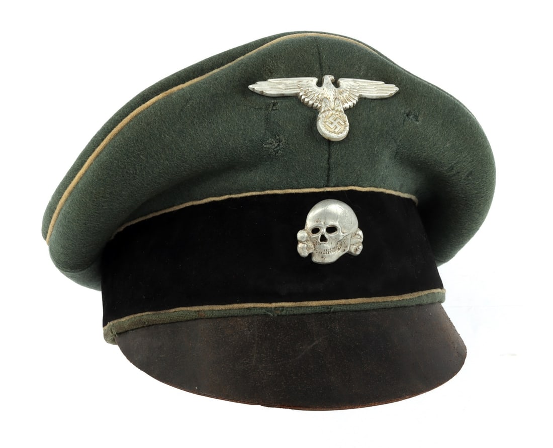 WWII GERMAN WAFFEN SS CRUSHER CAP VISOR: This field-grey visor cap features white piping and is adorned with an aluminum Reichsadler and Totenkopf. Manufactured by Ludwig Vogele, the piece is constructed with a leather visor and a silk linin