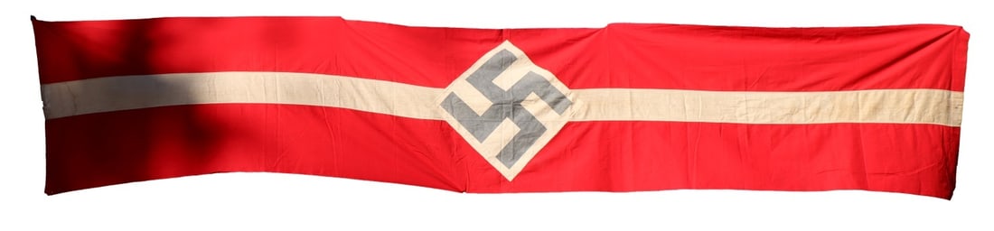 WWII GERMAN THIRD REICH HITLERJUGEND BANNER: A long banner for the Hitlerjugend, showing their symbol of a black swastika on a white diamond with striped red and white background. Non-fluorescing. 148 X 29 inches.