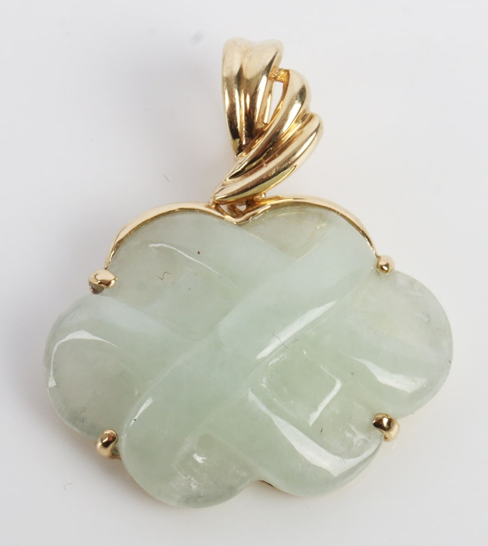 INFINITY KNOT PENDANT IN 14K GOLD 585 JADE: An infinity knot pendant carved from moss-in-snow nephrite. Stamped 'Hong Kong 14K.' Approximately 1 inch wide. This lot has a reserve.