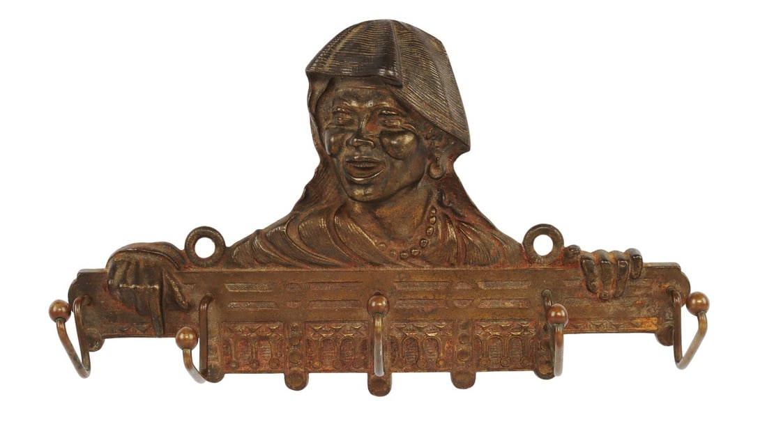 COAT RACK WITH THE STYLIZED HEAD OF AN AFRICAN: A cast iron, bronze-painted coat rack with the stylized head of an African woman. 12 X 8 inches.