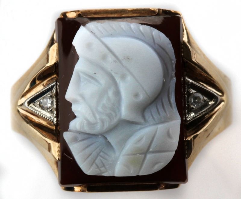 MENS VINTAGE 10K YG CARNELIAN & DIA. CAMEO RING: Classic deep red carnelian 'Conquistador' cameo, measuring 16 x 12.5mm, accented with two round single cut diamonds weighing approximately .02ct. each. 4mm wide at bottom of shank.