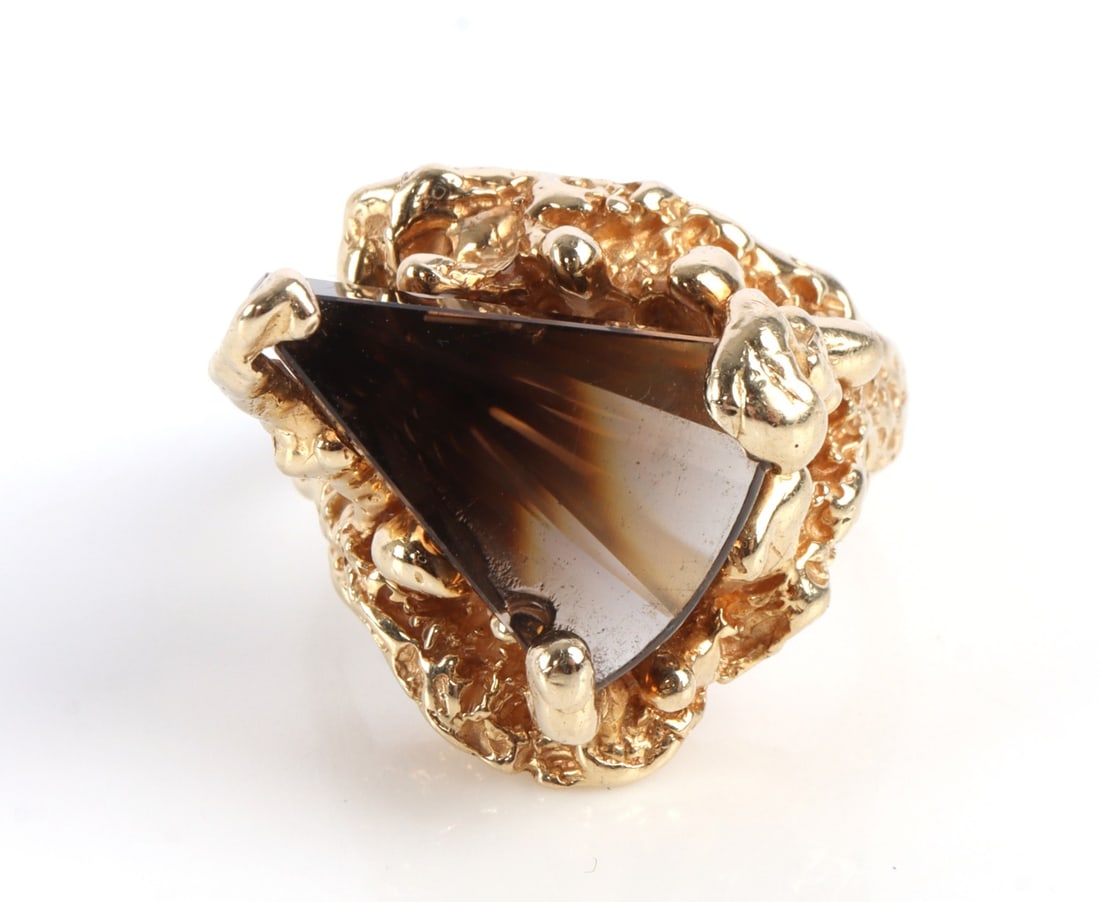 14KT BRUTALIST GOLD RING SMOKY QUARTZ: 14kt yellow gold ring. Brutalist design with a smoky quartz lighthouse lens cut center stone. Stone is 15.94 x 11.14mm. Size 7. This lot has a reserve.