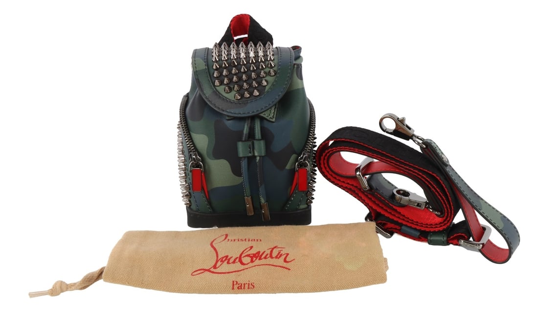 CHRISTIAN LOUBOUTIN EXPLORAFUNK BACK PACK CAMO: A Christian Louboutin Explorafunk cross body mini backpack for men. With Louboutin signature spikes and leather printed with a camo design. Red and black accenting. Comes with back straps and