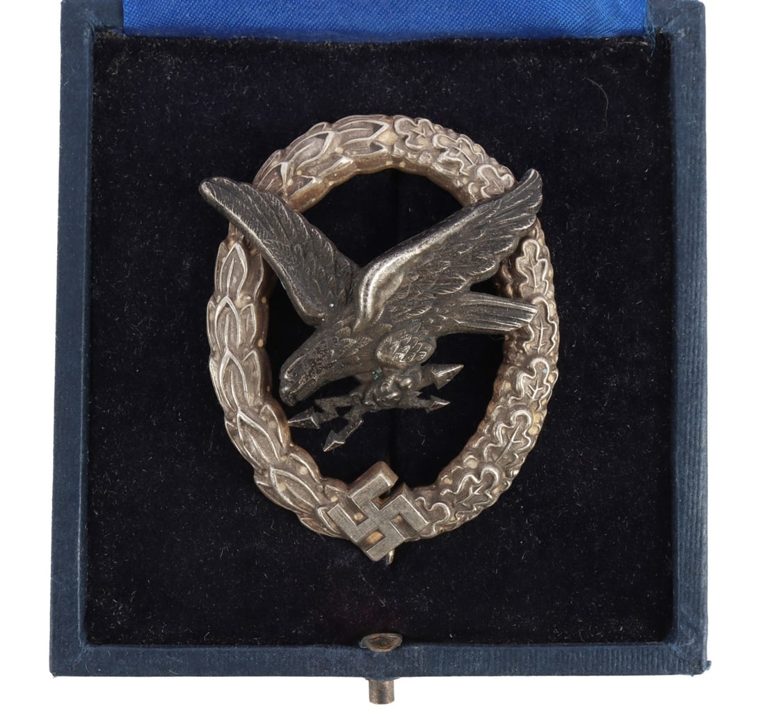 WWII GERMAN LUFTWAFFE RADIO OP OR GUNNER BADGE: Combined Radio Operator or Gunner badge. Early type with cut out swastika. Marked C.E. Juncker. Double riveted with thin pin and C catch. Measures 2 inches. Comes in case. This lot has a reserve.