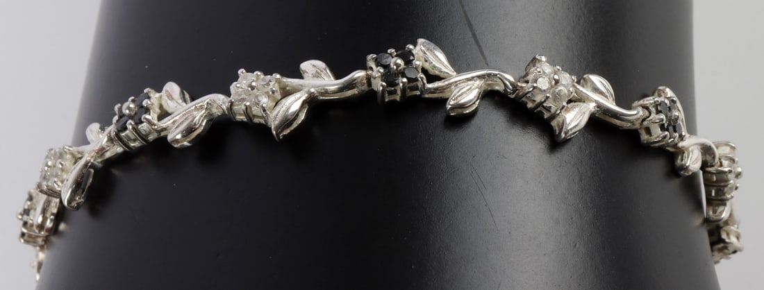 925 STERLING SILVER FLOWER LINK BRACELET.: Sterling silver bracelet with flower and vines. Flowers have black and white stones. Size 7.5 inches long. Stamped 925 on clasp. This lot has a reserve.