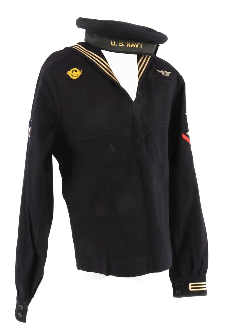 WWII US NAVAL CRACKERJACK UNIFORM FOR AIRCREW: The tunic and flat cap for a cracker jack sailor uniform of the Second World War., Air crew pin still on chest, ruptured duck on breast, and air crew patch on sleeve. Hat is a size 7. 17 inches should