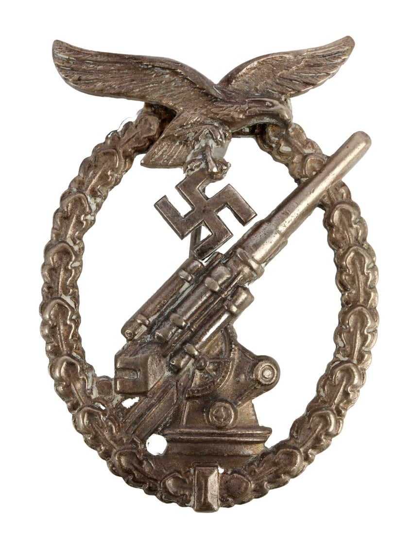 WWII GERMAN LUFTWAFFE FLAK BADGE C.E. JUNCKER: Solid-struck, of nickel silver. Reverse has barrel hinge, vertical wire pin and round crimped wire catch. Marked "?C.E. JUNCKER, BERLIN SW." Gross weight 41 grams.