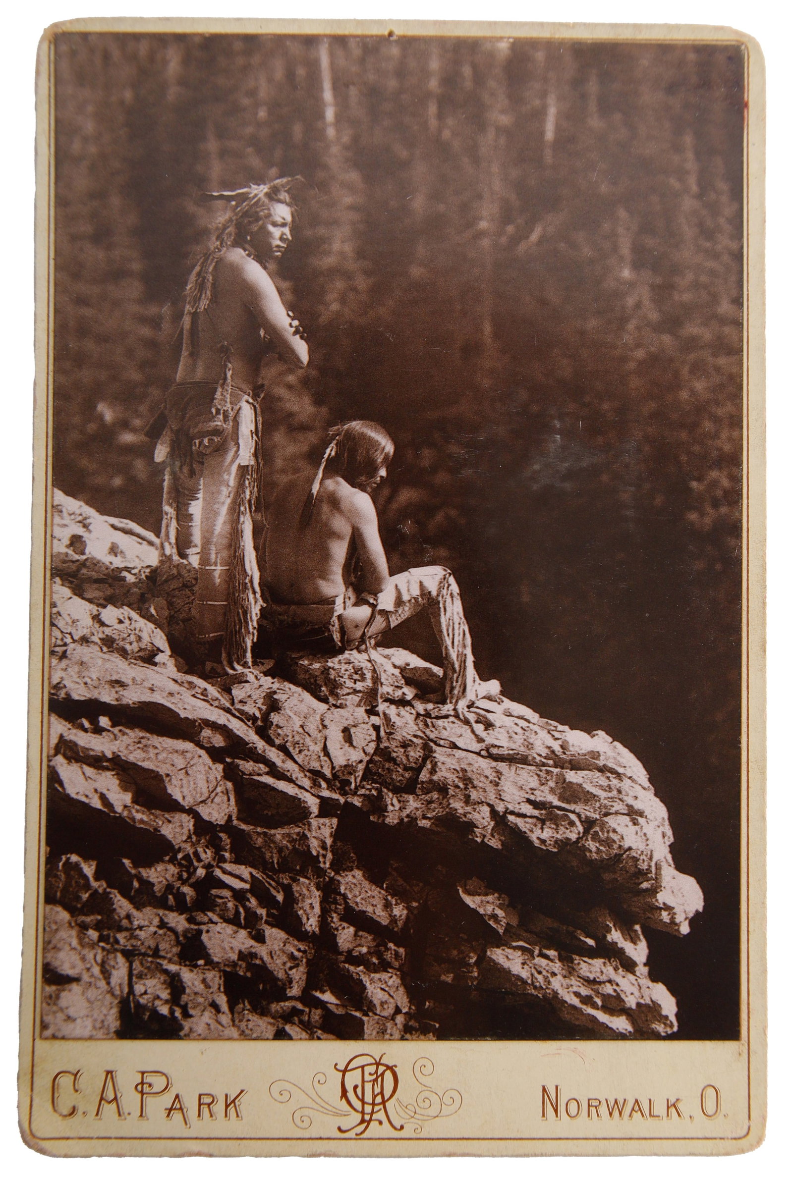 'The Canyon' Cabinet Photo of Blackfeet Reed: A cabinet photograph with a photo by Roland Reed, titled 'the Canyon,' depicting two Blackfeet members overlooking a nature scene. Cabinet photograph produced by C. A. Park of Norwalk, Ohio.
