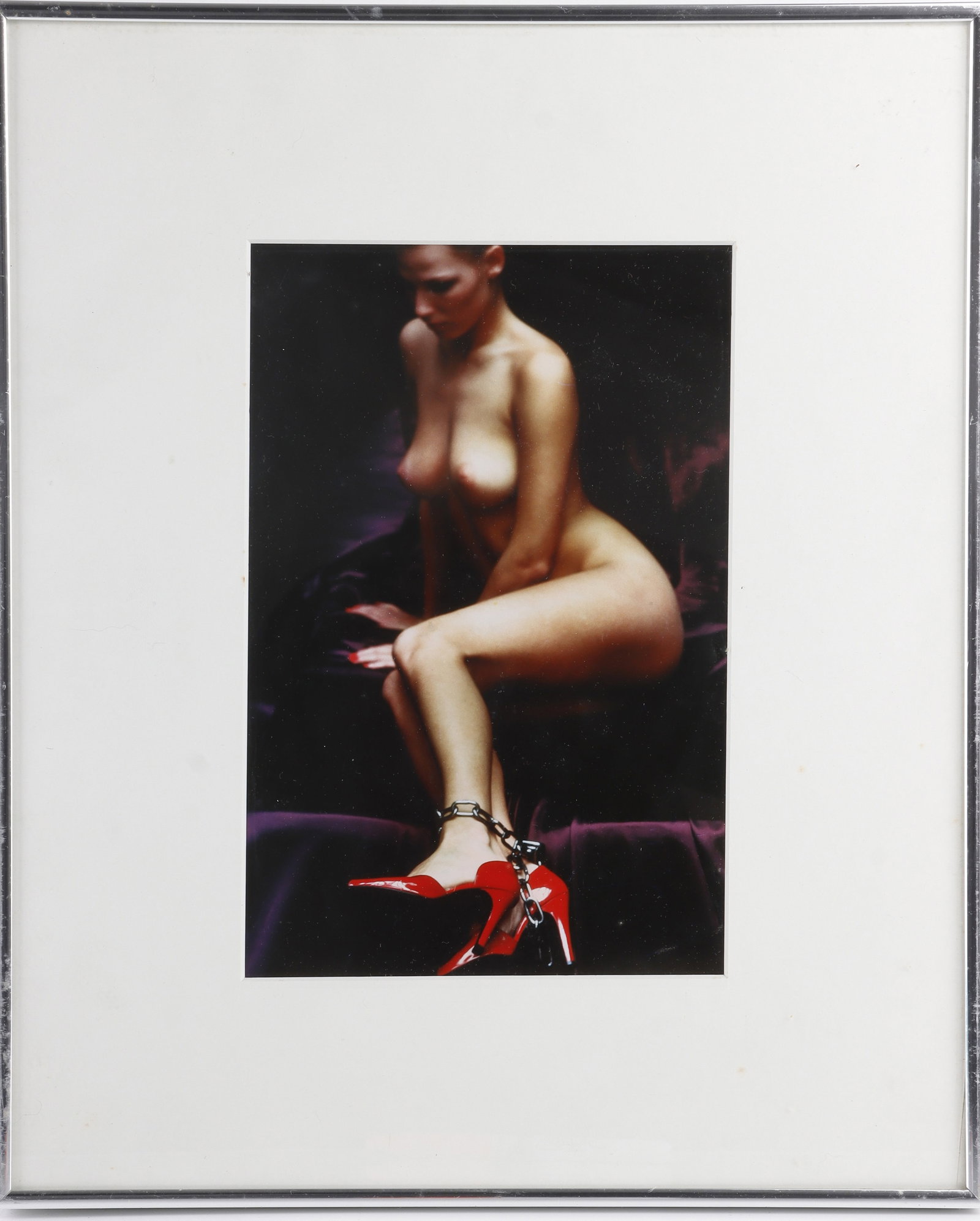 Helmut Newton Chained Woman: A copy of Helmut Newton's photograph, 'Chained Woman,' depicting a nude woman with chains around her ankle and vibrant red heels. Framed and matted. Frame is 14.5x17 inches. Helmut Newton (German-Aust