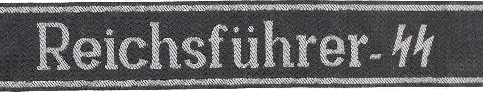 Reichsfuhrer SS Bevo Cuff Title WWII German: Reichsfuhrer SS BeVo embroidered cuff title. Length 21 inches. Width 1-1/4 inches. Black with silver BeVo SS lettering. | This lot has a reserve.
