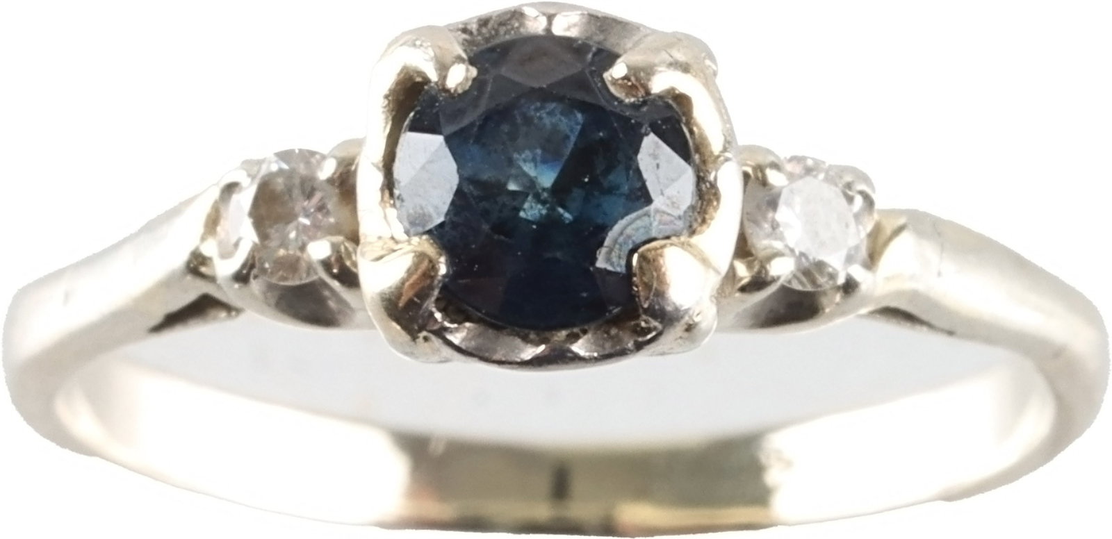 Antique 14K White Gold Sapphire and Diamond Ring: Single sapphire flanked by 2 melee point diamonds. The sapphire measures 4.55 X 2.94mm approximately. It weighs 2.35 grams. Size 7. Stamped 14KT. | This lot has a reserve.