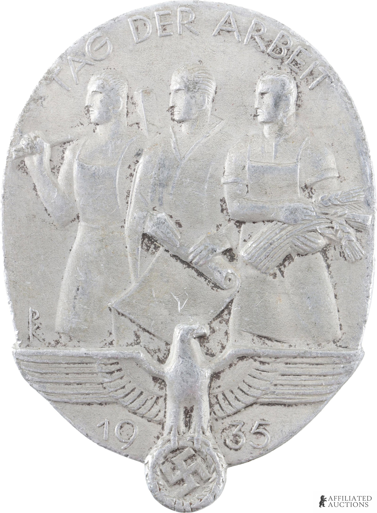 Third Reich 1935 Labor Day Tinnie Pin: Third Reich 1935 Labor Day Tinnie Pin. On the obverse side this pin depicts three people: one with a hammer, one a piece of paper, and one with grain. The inscription on the obverse side the inscripti