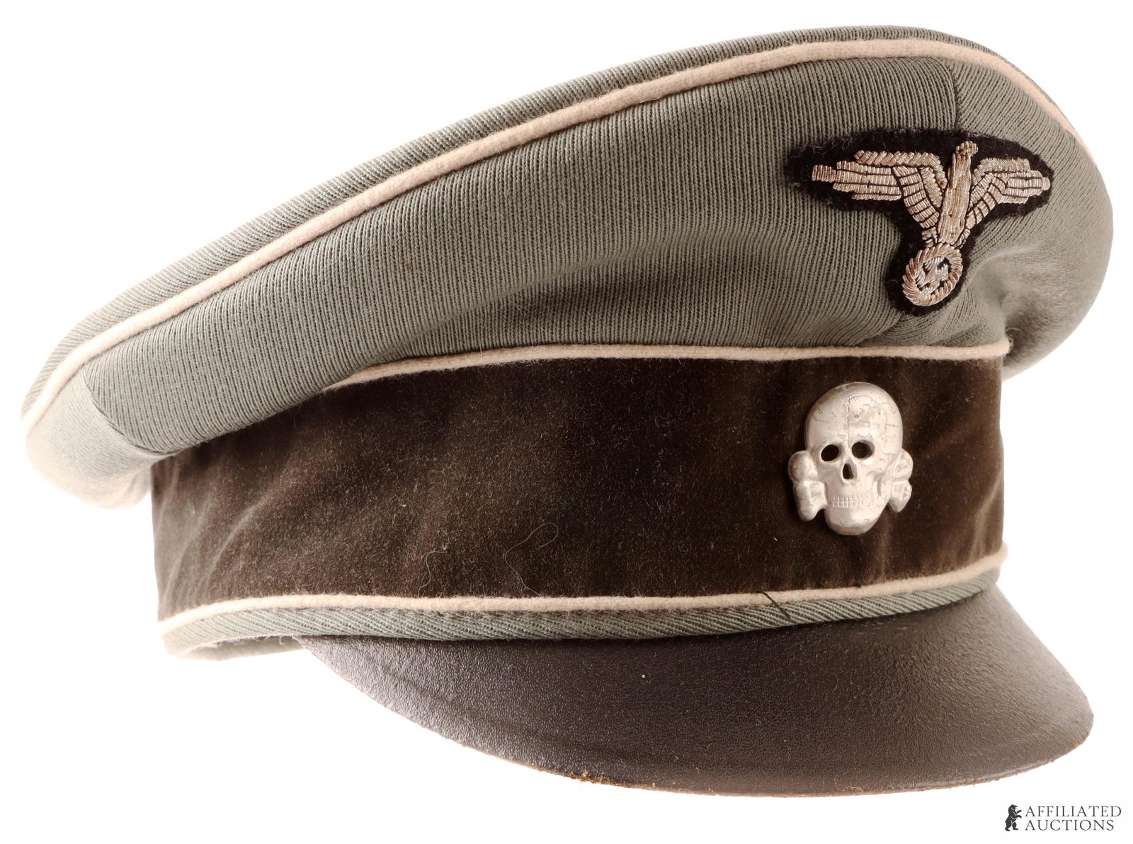 Waffen SS Officer Visor WWII German Reich: Gabardine construction. Exterior features bullion reichsadler with aluminum totenkopf. Visor is leather construction. Black velvet band and white piping. Interior liner is rayon with maker stamp. Leat
