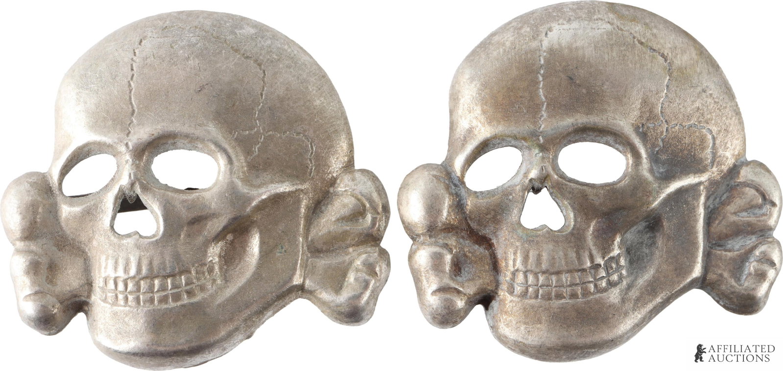 Two SS Officer Visor Totenkopf Pins WWII German: Two SS Officer visor pins. Marked D.S. & M Ges. Gesch. They measure 28.80mm. Nickel or zinc construction. | This lot has a reserve.