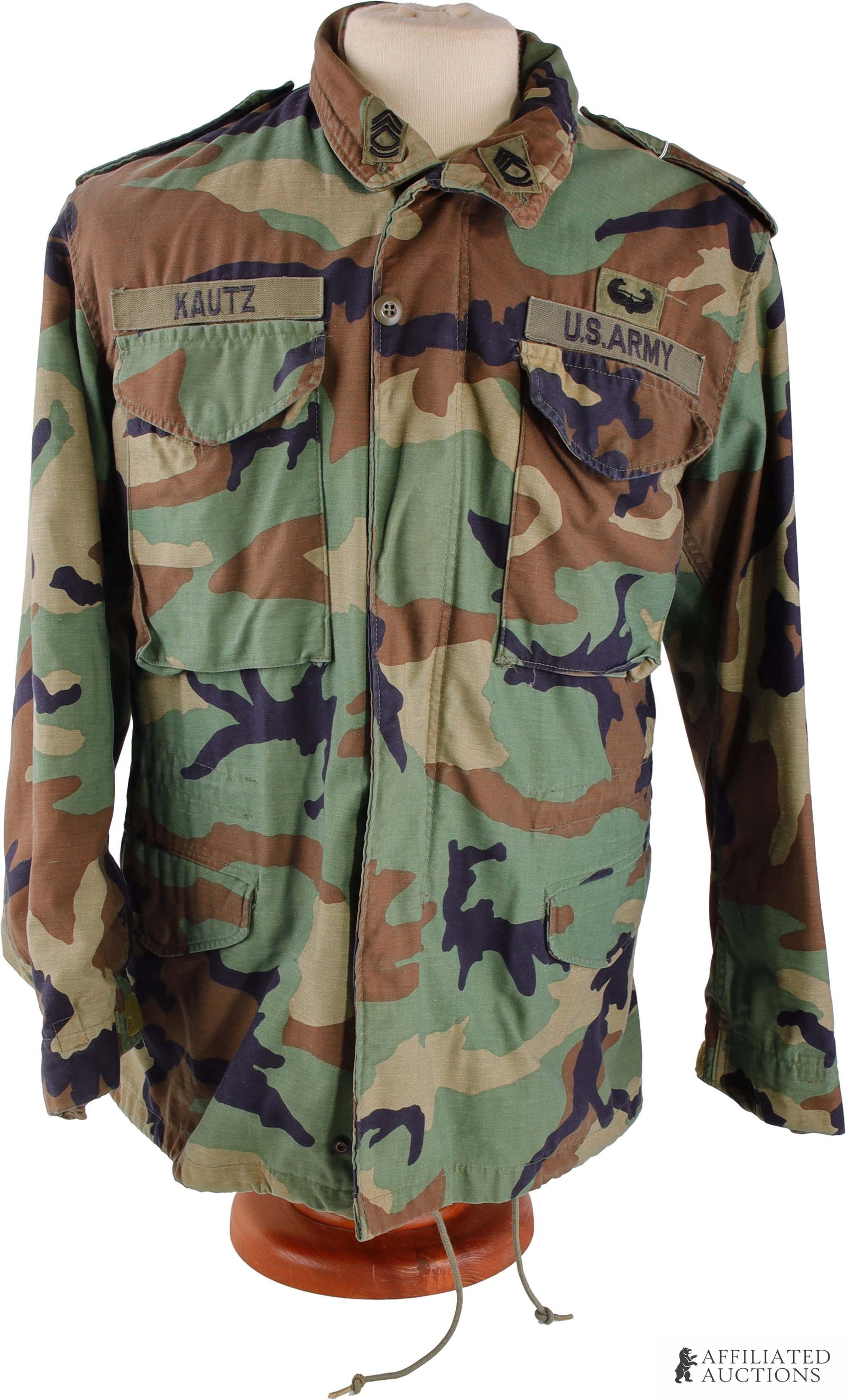 M65 Cold Weather Coat US Army Named with Patches: An M65 cold weather coat with patches, in the woodland camo pattern. Current unit designation patch indicates the 2nd Armored Division 'Hell on Wheels,' while combat patch on right shoulder points to 
