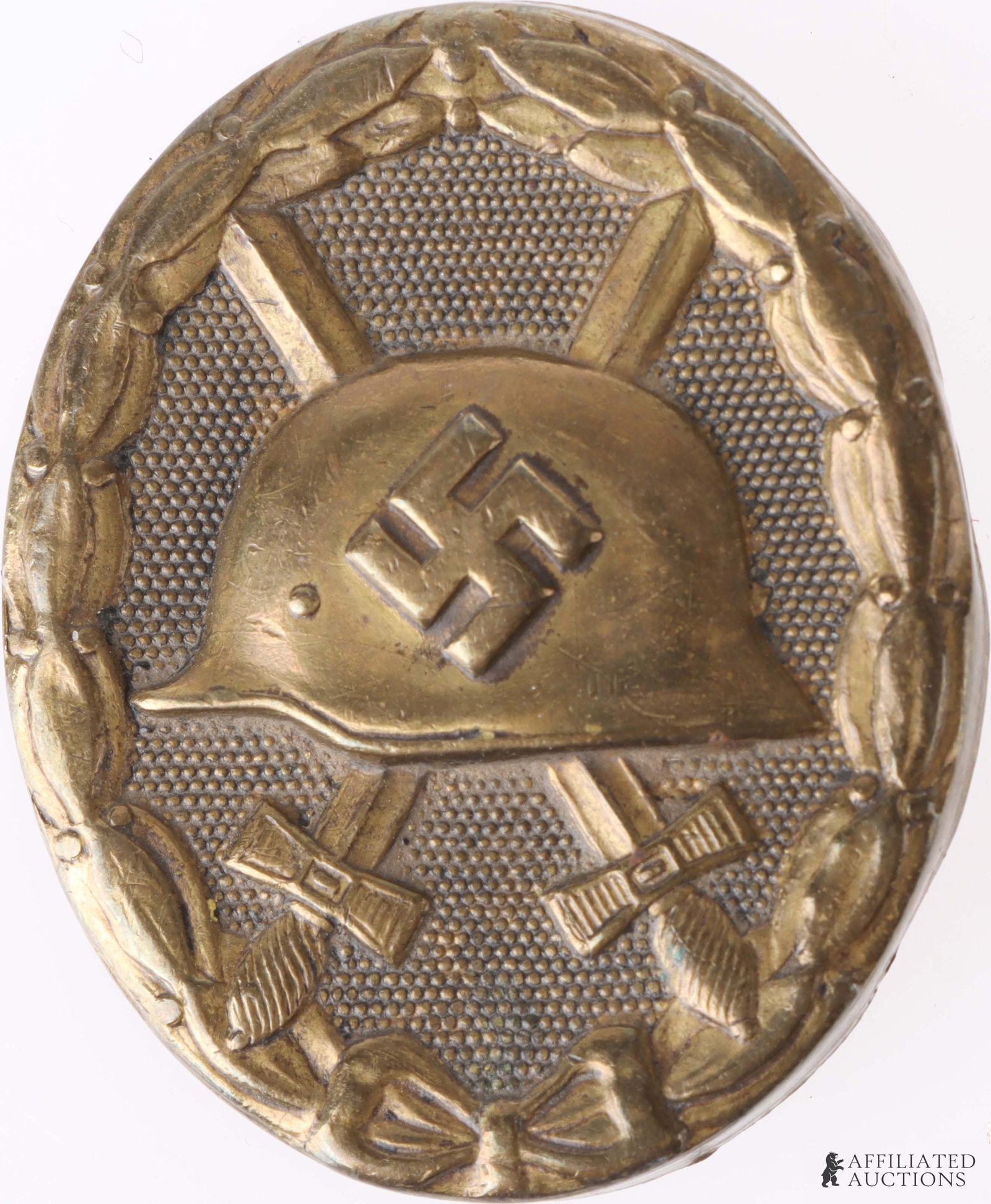 German Military Wound Badge Gold WW2 Third Reich: A WW2 German Gold Wound Badge. Features a steel helmet bearing a swastika, centered over a pair of crossed swords, all surrounded by an oak leaf laurel with a bow at the bottom center. This badge was 