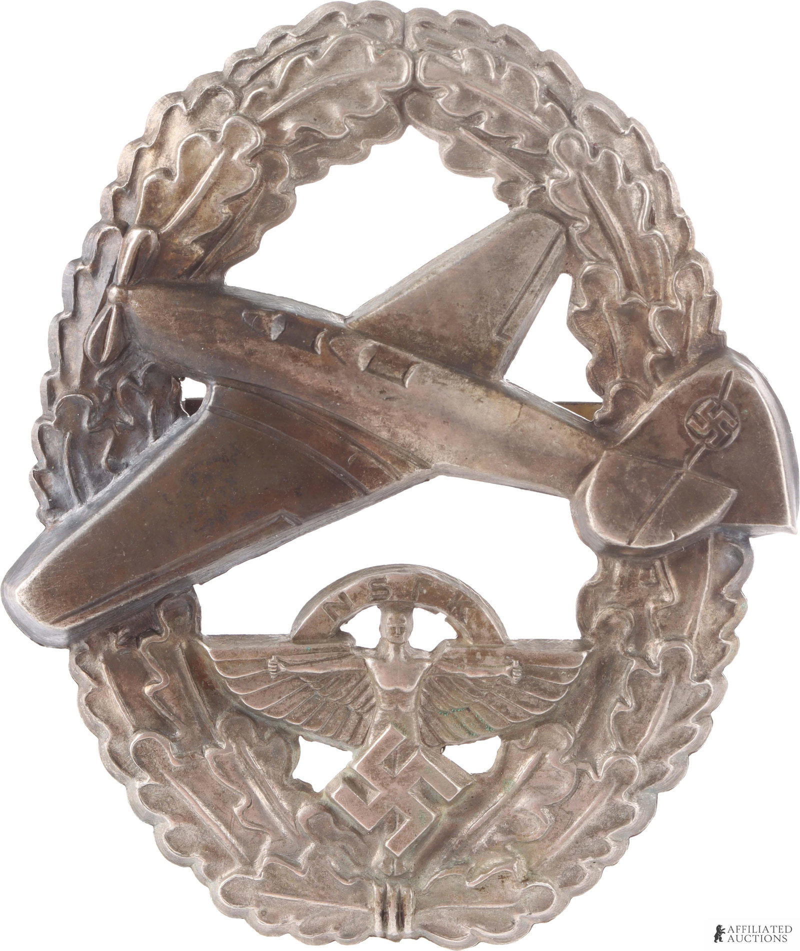 WWII German NSFK Powered Aircraft Badge: Oak leaf pattern with NSFK insignia and aircraft. Stamped construction. Horizontal Reverse marked 'Ges Gesch' and numbered '22639.' It measures 54.94mm.