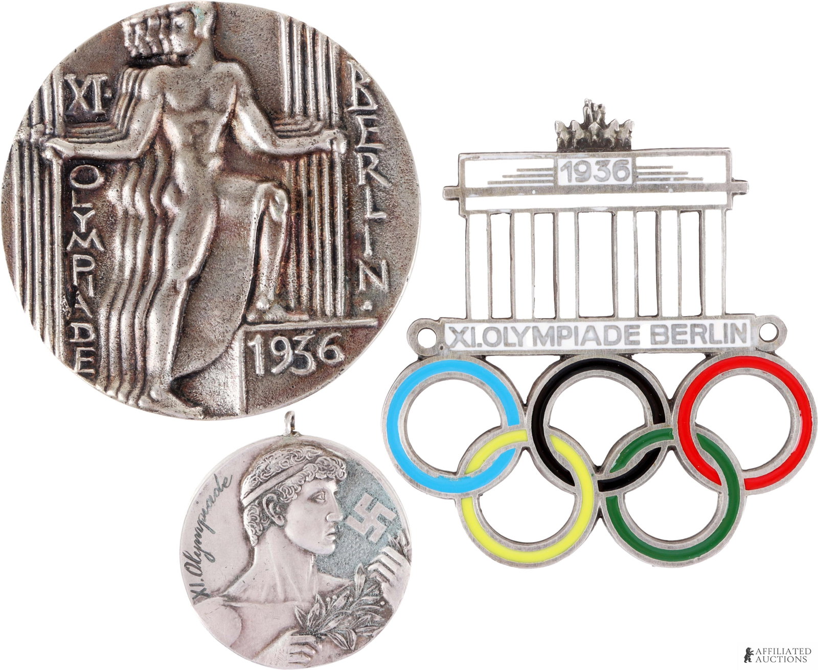 1936 Summer Olympics Memorabilia Lot of 3: A lot of three medals/badges commemorating the 1936 Berlin Summer Olympics. Includes the following: 1) a car grille badge featuring the Brandenburg Gate and Olympic rings; 2) a silver-finished bronze 